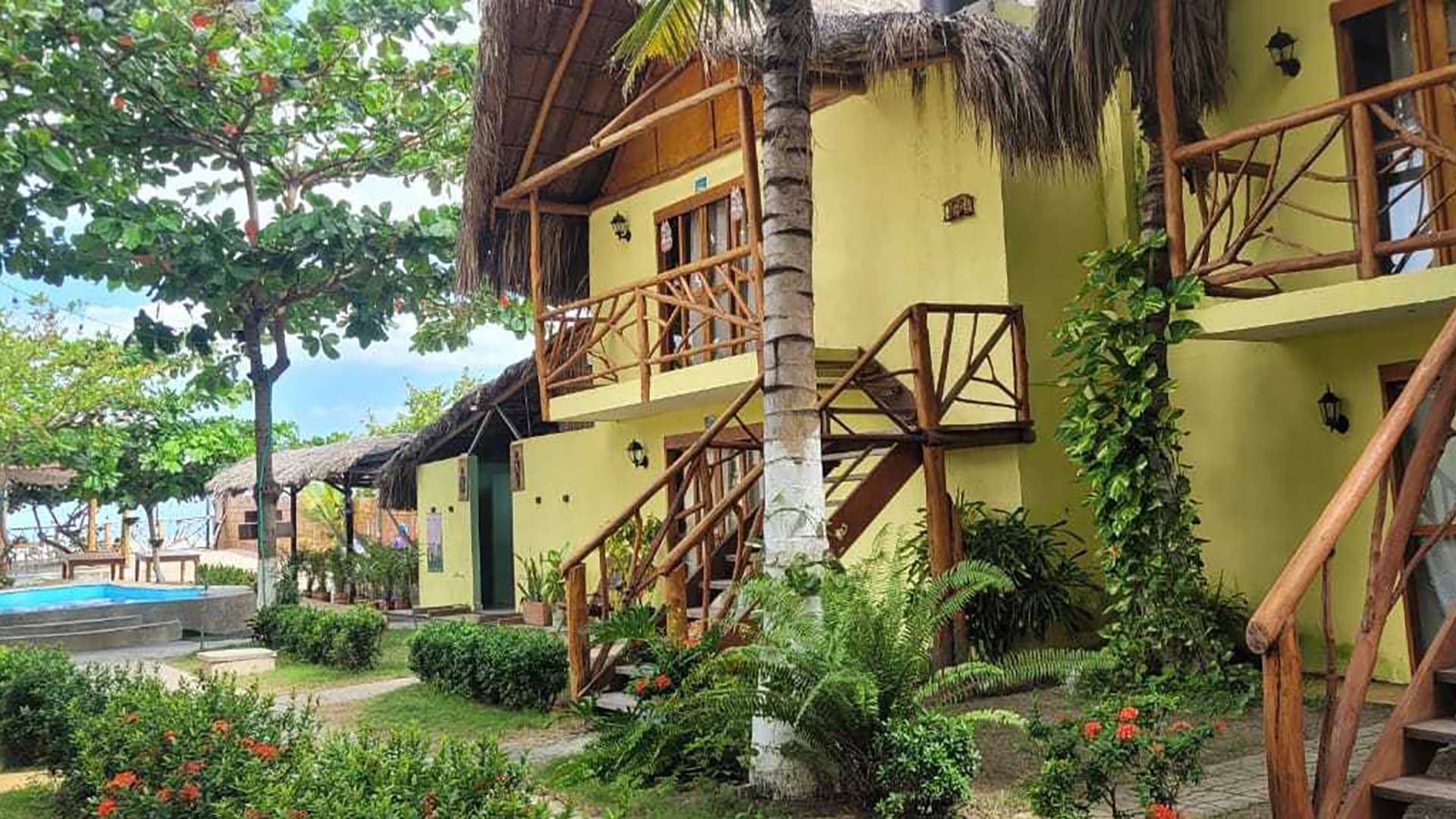 A tropical resort featuring colorful cottages, lush greenery, and a pool.