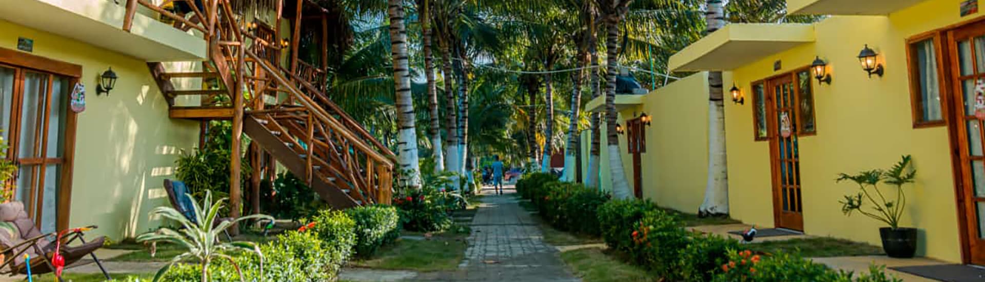 A serene pathway lined with palm trees and colorful cottages in a tropical setting.